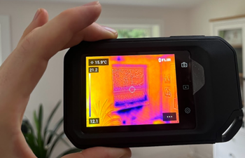 The thermal imaging camera showing air leakage under a window frame.